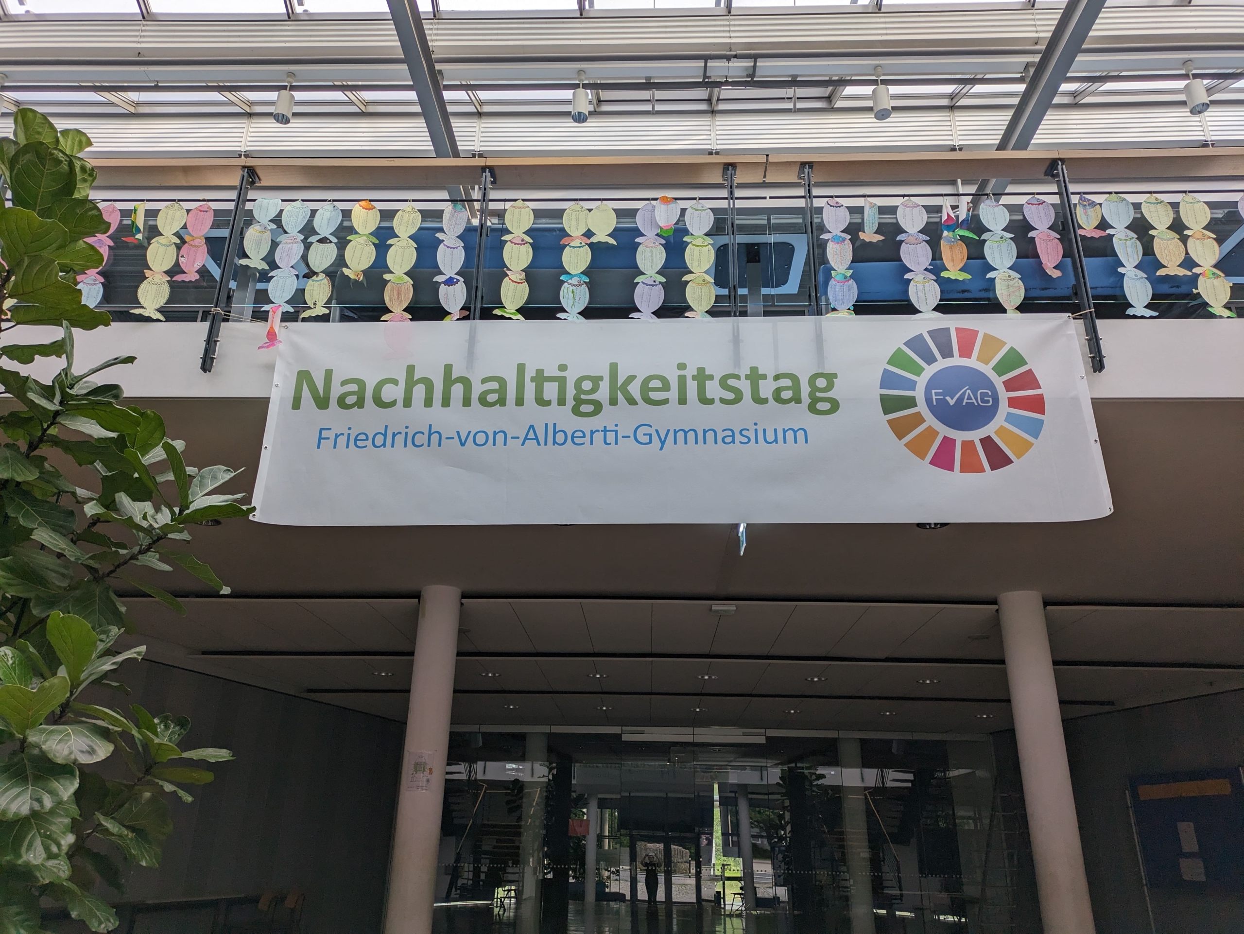Blick aus der Aula hoch auf die Empore.Zu sehen ist ein Banner mit der Aufschrift "Nachhaltigkeitstag Friedrich-von-Alberti-Gymnasium".