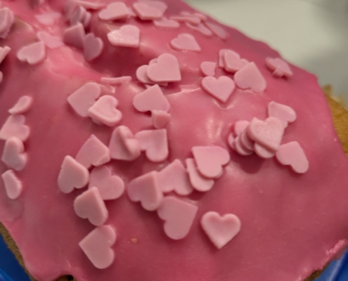 Foto eines Kuchens mit pinker Glasur und rosafarbenen Deko-Herzchen.