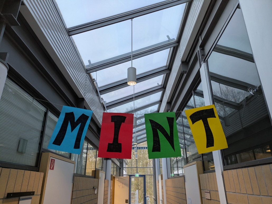 Foto eines Schulflurs. Unter der Decke ist ein Seil mit den vier Buchstaben MINT gespannt.