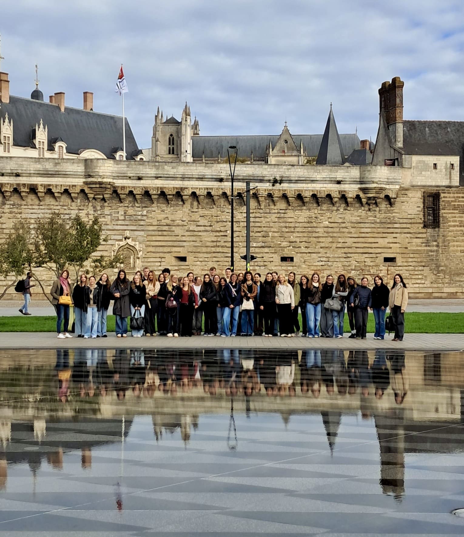 Gruppenfoto einer Schülergruppe vor dem Schloss in Nantes. Im Vordergrund ist eine Wasserfläche erkennbar.