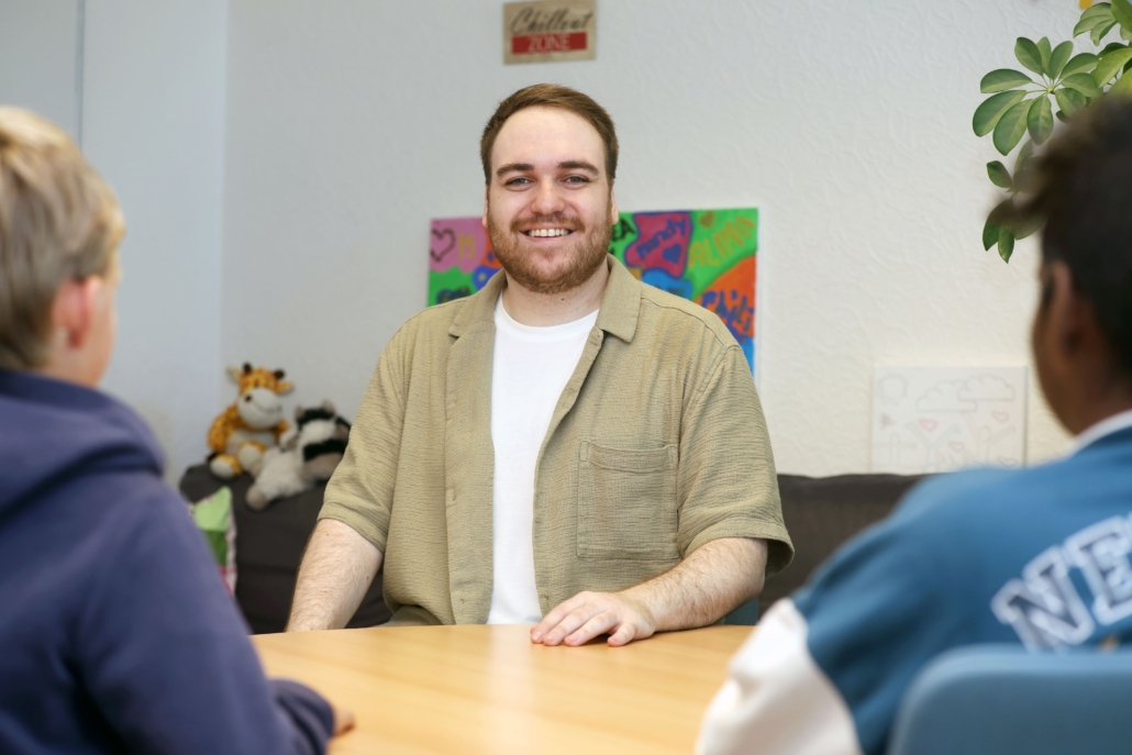 Foto von Hr. Lohwasser, im Vordergrund ein Tisch und verschwommene Hinterköpfe zweier Schüler.
