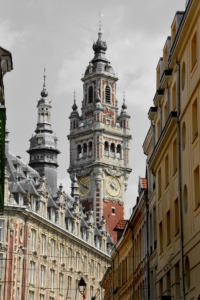 Foto einer Kirchturmspitze in Lille. Im Vordergrund: Historische Dächer.