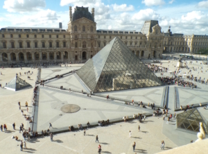 Foto der Glaspyramide des Louvre in Paris mit vielen Menschen, die warten.