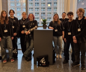 Gruppenfoto von Mitgliedern der MKT-AG, die um einen Stehtisch herum stehen. Im Hintergrund ist ein großes Fenster zu sehen.
