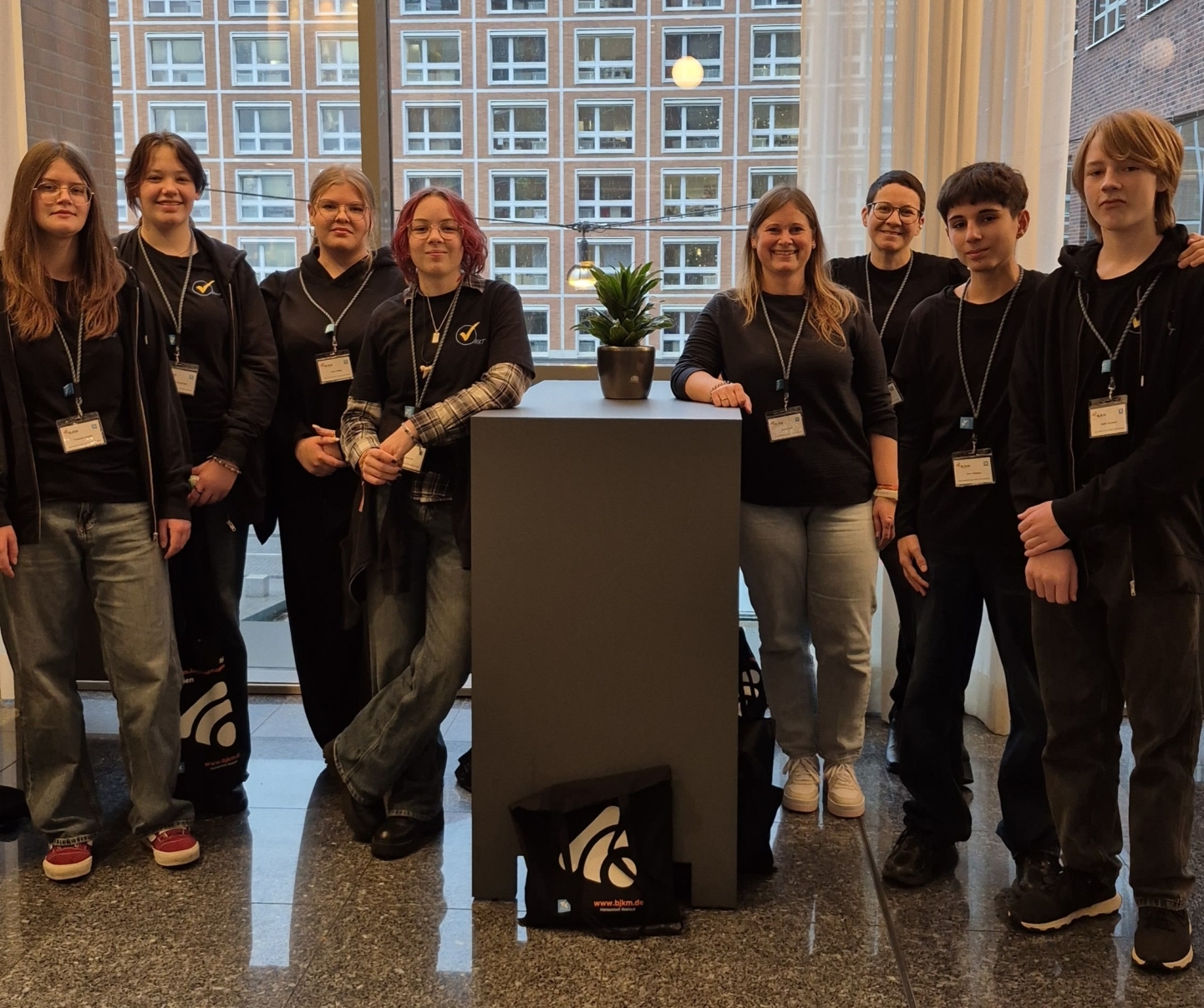 Gruppenfoto von Mitgliedern der MKT-AG, die um einen Stehtisch herum stehen. Im Hintergrund ist ein großes Fenster zu sehen.