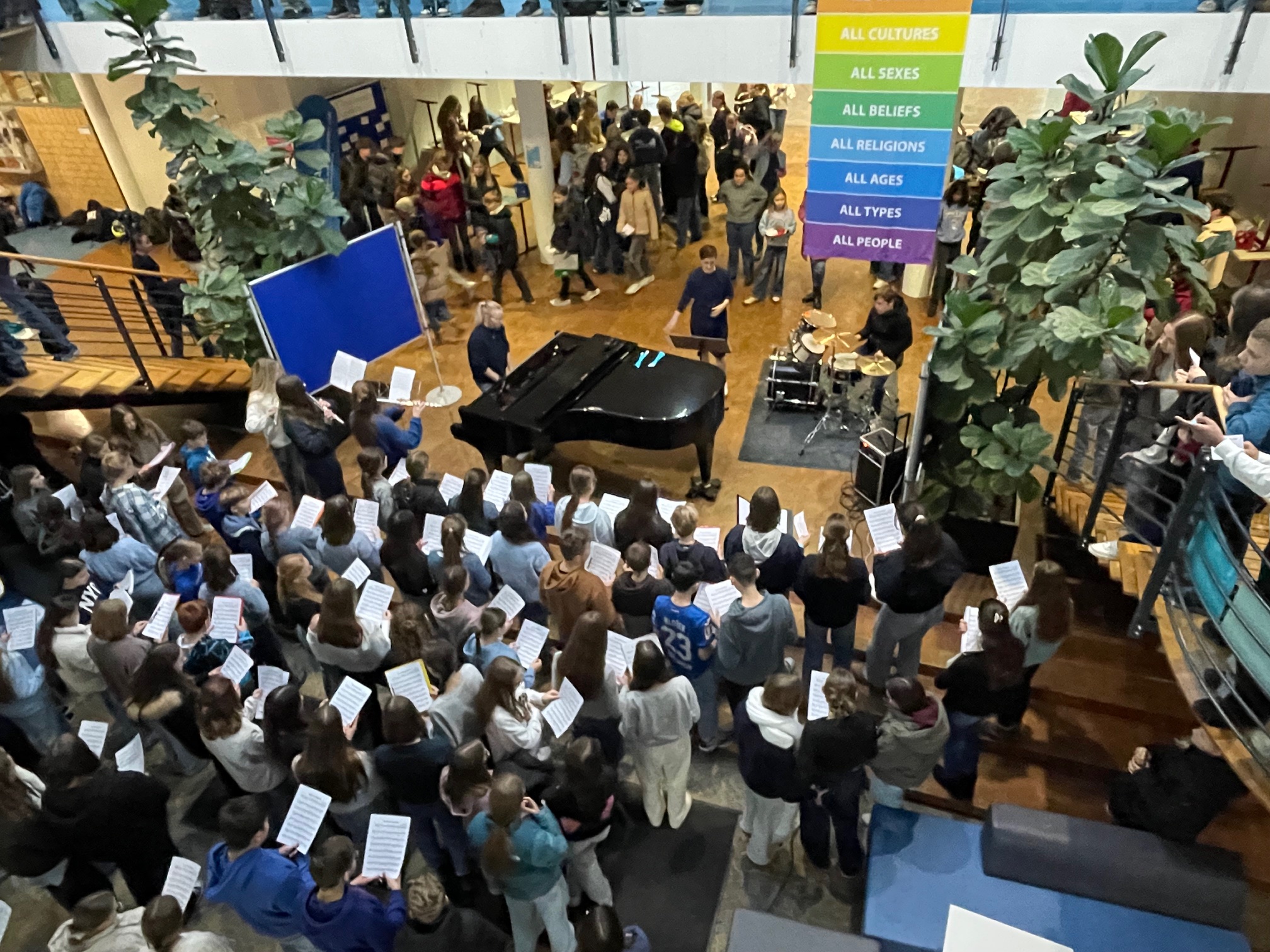 Bild vom Blue Day. Singende Schülerinnen und Schüler stehen im Foyer.