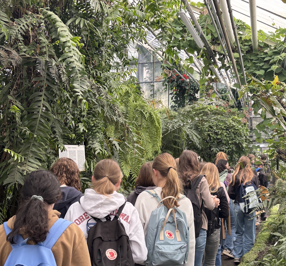 Eine Schülergruppe geht durch ein Gewächshaus des botanischen Gartens