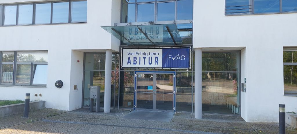 Foto des Eingangsbereich. Auf einem Banner über der Tür ist neben dem FvAG-Schullogo der Text "Viel Erfolg beim Abitur" zu lesen