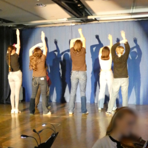 Schülerinnen und Schüler tanzen auf der Bühne.